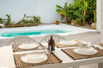 a table with white plates and a bottle of wine at Villa Tailan con piscina y jacuzzi privado in Chiclana de la Frontera