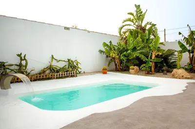 a swimming pool in a backyard with a water fountain at Villa Tailan con piscina y jacuzzi privado in Chiclana de la Frontera