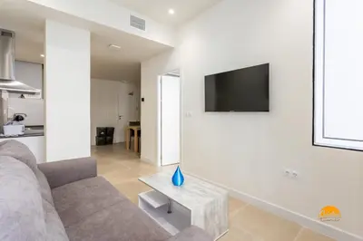 a living room with a couch and a tv on a wall at Delfin Azul by Cadiz Time in Cádiz
