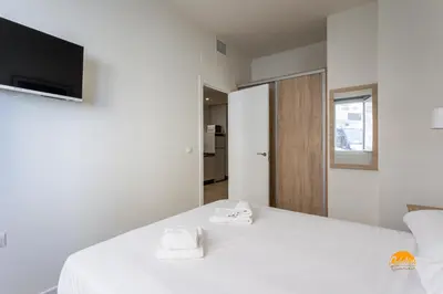 a bedroom with a white bed with a tv on the wall at Delfin Azul by Cadiz Time in Cádiz