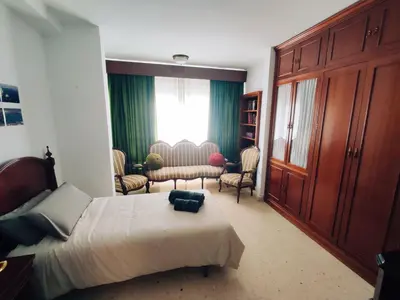 a bedroom with a bed and a couch and a window at Casa Comodoro in Cádiz