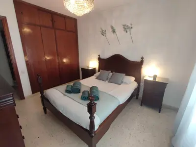 a bedroom with a large bed with a wooden headboard at Casa Comodoro in Cádiz