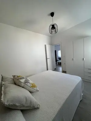 a white bedroom with a bed with two pillows at Capillita de Bajo Guía in Sanlúcar de Barrameda