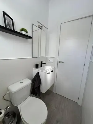 a white bathroom with a toilet and a sink at Capillita de Bajo Guía in Sanlúcar de Barrameda