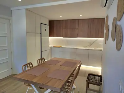 a kitchen with a wooden table and chairs in a room at Modern Beach Front Home by Chiclana Dreams in Chiclana de la Frontera