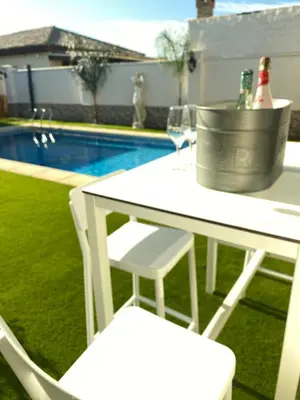 a white table and chairs next to a pool at Musa del Paraíso in Novo Sancti Petri