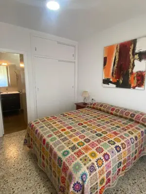 a bedroom with a bed with a colorful quilt at Casitasmanoli Fuente del Gallo in Conil de la Frontera