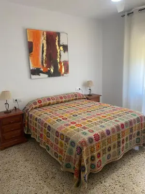 a bedroom with a bed and a painting on the wall at Casitasmanoli Fuente del Gallo in Conil de la Frontera