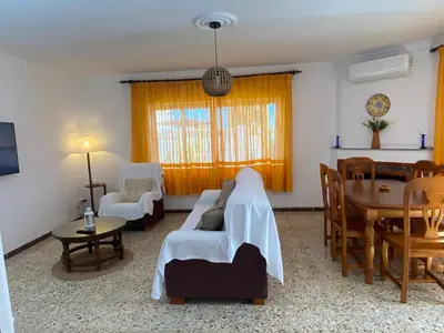 a living room with a couch and a dining room at Casitasmanoli Fuente del Gallo in Conil de la Frontera