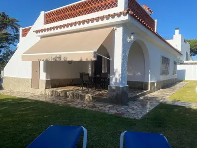 a white house with awning and chairs in the yard at Casitasmanoli Fuente del Gallo in Conil de la Frontera