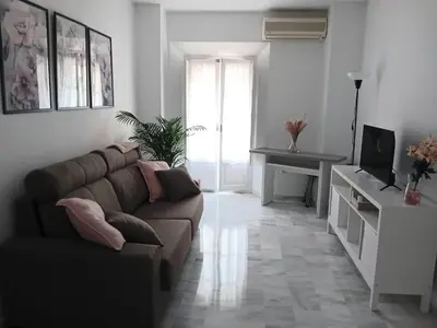a living room with a couch and a television at Apartamento con encanto en el corazón de la ciudad in Jerez de la Frontera