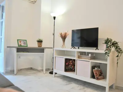 a living room with a tv on a white entertainment center at Apartamento con encanto en el corazón de la ciudad in Jerez de la Frontera