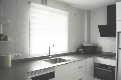a white kitchen with a sink and a window at Apartamento con encanto en el corazón de la ciudad in Jerez de la Frontera