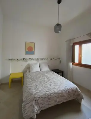 a bedroom with a large bed with a yellow stool at Apartamento Céntrico in El Puerto de Santa María