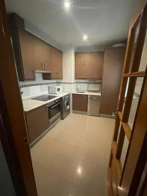 a large kitchen with wooden cabinets and appliances at Apartamento Céntrico in El Puerto de Santa María