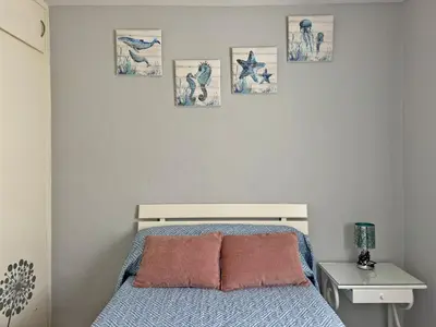 a bedroom with a bed and four pictures on the wall at Apartamento El Faro - Ole Solutions in El Puerto de Santa María