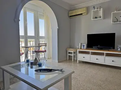 a living room with a glass table and a television at Apartamento El Faro - Ole Solutions in El Puerto de Santa María