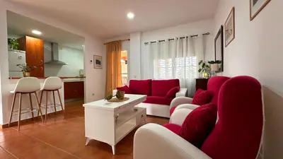 a living room with a red couch and a kitchen at Mika's House Valley in Sanlúcar de Barrameda
