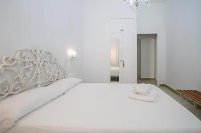 a white bedroom with a white bed with a silver headboard at Montera Suite Cádiz in Cádiz