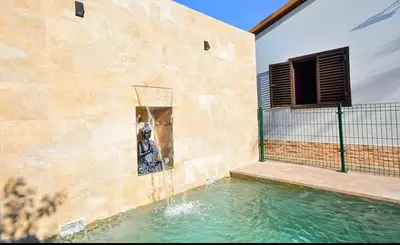 a building with a basketball hoop next to a swimming pool at Chalet con encanto en Conil SOLO FAMILIAS Y PAREJAS in Conil de la Frontera