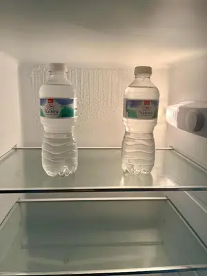two water bottles sitting on a glass shelf in an empty refrigerator at Lindo Pisito Sanlucar Calle Ancha in Sanlúcar de Barrameda