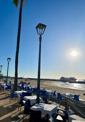 a beach with tables and chairs and a street light at Lindo Pisito Sanlucar Calle Ancha in Sanlúcar de Barrameda