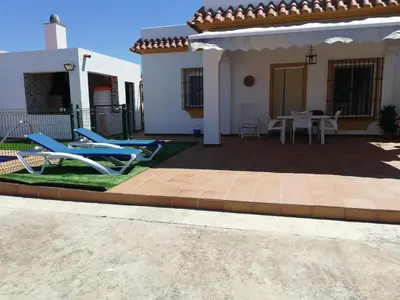 a house with a patio with chairs and a table at Chalet Casa Paqui solo familias o parejas in Conil de la Frontera