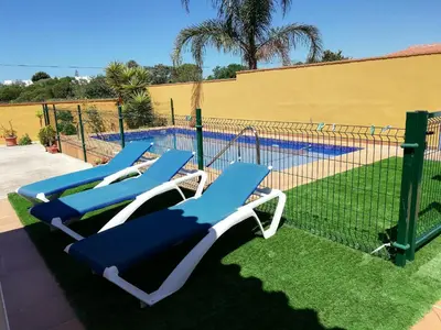 a group of lounge chairs in front of a pool at Chalet Casa Paqui solo familias o parejas in Conil de la Frontera