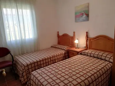 two beds in a hotel room with a window at Chalet Casa Paqui solo familias o parejas in Conil de la Frontera