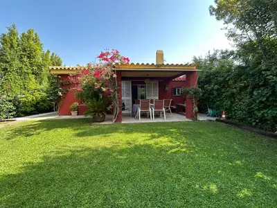 a small red house with a grass yard at Villa Rocio in El Puerto de Santa María