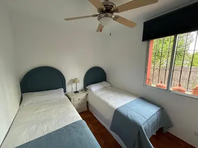 two beds in a bedroom with a ceiling fan at Villa Rocio in El Puerto de Santa María