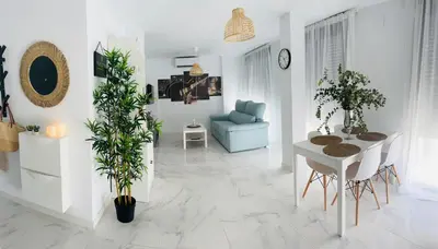 a white living room with a table and a chair at Puertas del Sol 11 in Jerez de la Frontera