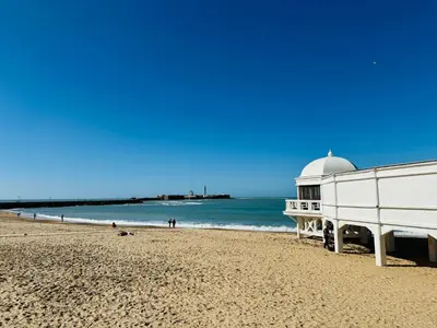 a white building on a beach with the ocean at Ático Sonnenschein in Jerez de la Frontera
