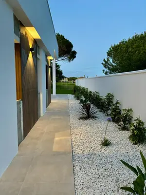 a walkway with plants next to a white fence at Poniente Beach House in Chiclana de la Frontera