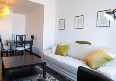 a living room with a white couch and a table at Ático Plaza Del Cabildo A 10 Min De La Playa in Sanlúcar de Barrameda