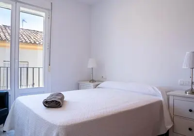 a white bedroom with a bed and a window at Ático Plaza Del Cabildo A 10 Min De La Playa in Sanlúcar de Barrameda