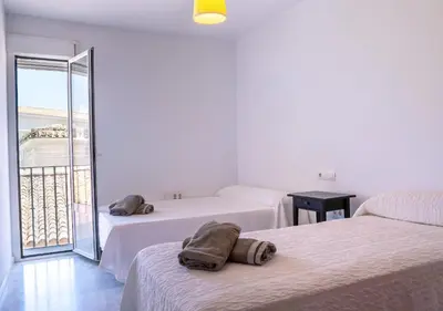 a hotel room with two beds and a balcony at Ático Plaza Del Cabildo A 10 Min De La Playa in Sanlúcar de Barrameda