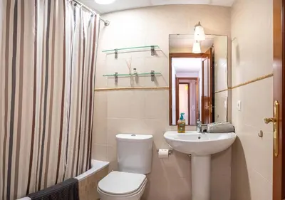a bathroom with a toilet and a sink and a mirror at Ático Plaza Del Cabildo A 10 Min De La Playa in Sanlúcar de Barrameda