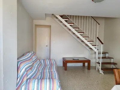 a living room with a couch and a staircase at La Longuera - Playa Cruz del Mar in Chipiona