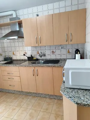 a kitchen with wooden cabinets and a sink at La Longuera - Playa Cruz del Mar in Chipiona