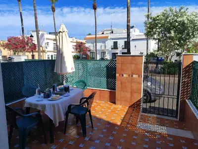 a table and chairs on a patio with a umbrella at La Longuera - Playa Cruz del Mar in Chipiona