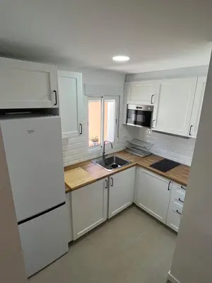 a kitchen with white cabinets and a white refrigerator at Apartamento Chiclana de la frontera in Chiclana de la Frontera