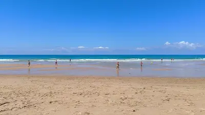 a group of people standing in the water on a beach at Apartamento Chiclana de la frontera in Chiclana de la Frontera