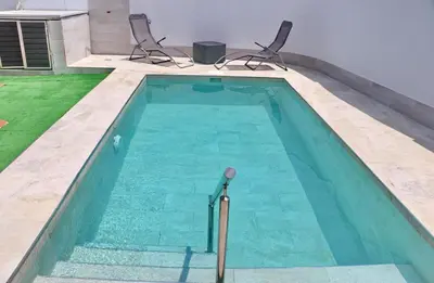 a swimming pool with two chairs in a house at Casa Pradillo in Conil de la Frontera