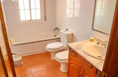a white bathroom with a toilet and a sink at Casa Pradillo in Conil de la Frontera