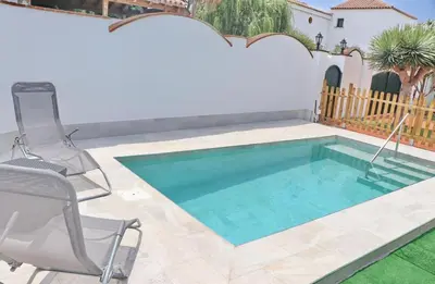 a swimming pool with two chairs and a table at Casa Pradillo in Conil de la Frontera