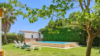 a backyard with a swimming pool with chairs and a tree at Villa Alegría Conil de la Frontera by Ruralidays in Conil de la Frontera