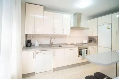 a kitchen with white cabinets and a sink at Piso Ángel in Sanlúcar de Barrameda