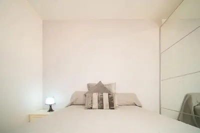 a white bedroom with a bed with a mirror at Piso Ángel in Sanlúcar de Barrameda