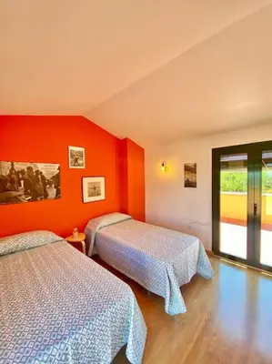 two beds in a room with orange walls at Amplio adosado a pocos metros de la playa in Poblado de Sancti Petri